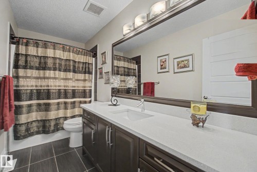 Bathroom featuring dark wood-finish vanity with dual sinks, light-toned countertop, and an expansive wall-mounted mirror - 805 Hodgins Road, Edmonton, AB - Indoor