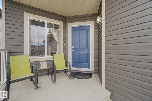 Inviting front porch featuring gray horizontal siding and a contrasting blue entry door - 805 Hodgins Road, Edmonton, AB - Outdoor With Deck Patio Veranda With Exterior