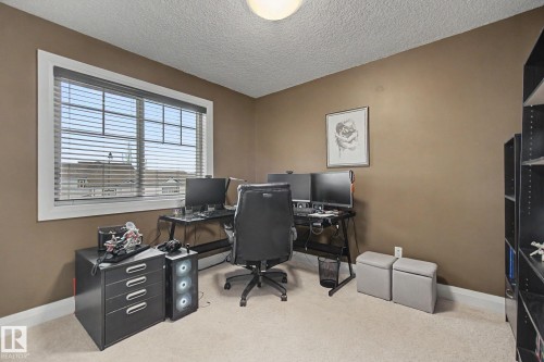Neutral-toned walls and light-colored carpet provide a versatile backdrop for this room, featuring a double window with horizontal blinds - 805 Hodgins Road, Edmonton, AB - Indoor Photo Showing Office