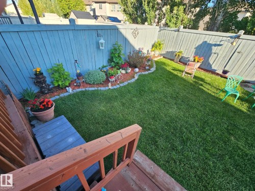 Fenced backyard with a manicured lawn, a garden bed with decorative edging, and a wooden deck - 805 Hodgins Road, Edmonton, AB - Outdoor