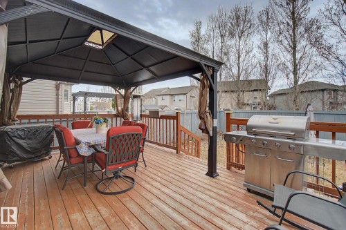 Expansive wood-finish deck featuring a dedicated gazebo area, built-in wooden railing, and a stainless steel outdoor grill - 805 Hodgins Road, Edmonton, AB - Outdoor With Deck Patio Veranda With Exterior