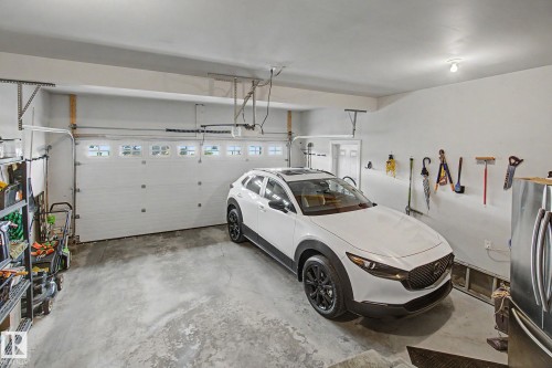 Attached garage featuring a sectional overhead door with upper window inserts, concrete flooring, and painted interior walls - 805 Hodgins Road, Edmonton, AB - Indoor Photo Showing Garage