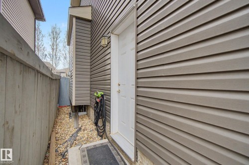Exterior side entrance featuring a white door, an outdoor wall light fixture, and horizontal siding - 805 Hodgins Road, Edmonton, AB - Outdoor