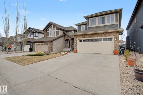 Two-story residence featuring a two-car garage with overhead windows, stone veneer accents, and horizontal siding - 805 Hodgins Road, Edmonton, AB - Outdoor With Facade