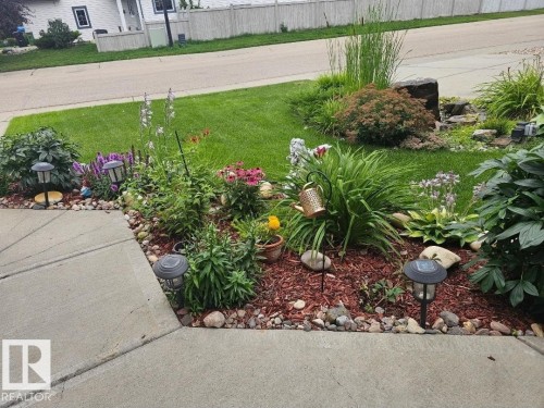 Landscaped front yard featuring a variety of mature plantings, decorative rock borders, and ground cover - 805 Hodgins Road, Edmonton, AB - Outdoor
