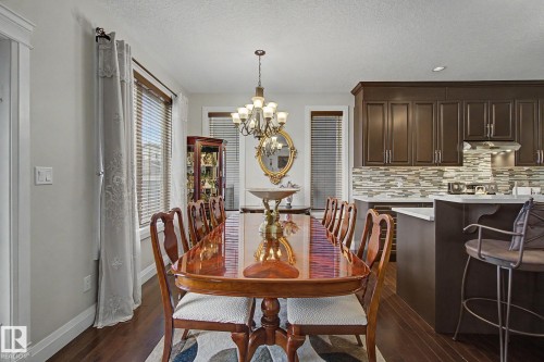 Dining area featuring dark wood-finish flooring, a brass chandelier, and windows with blinds - 805 Hodgins Road, Edmonton, AB - Indoor Photo Showing Dining Room