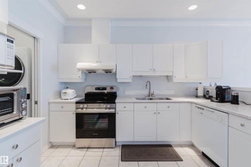 White kitchen cabinetry complemented by light countertops and a tile backsplash - 19 1659 Jamha Road, Edmonton, AB - Indoor Photo Showing Kitchen With Double Sink