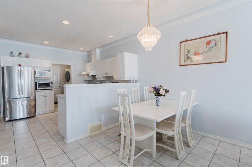 Combined kitchen and dining area featuring ceramic tile flooring, white cabinetry, and stainless steel refrigerator - 19 1659 Jamha Road, Edmonton, AB - Indoor Photo Showing Dining Room