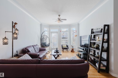 Living area featuring a bay window with multiple vertical windows, crown molding, a ceiling fan, and wood-finish flooring - 19 1659 Jamha Road, Edmonton, AB - Indoor Photo Showing Living Room