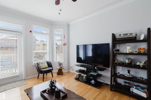 Living area featuring light wood-finish flooring, bay window with blinds, white crown molding, and a ceiling fan - 19 1659 Jamha Road, Edmonton, AB - Indoor Photo Showing Living Room