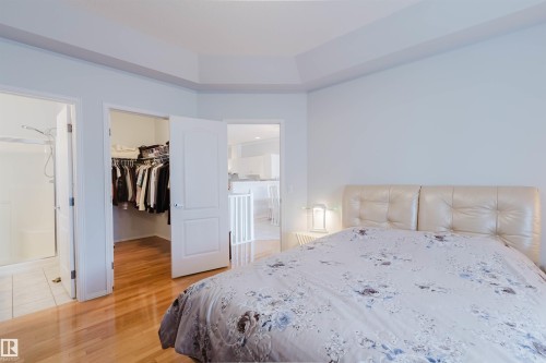 Bedroom space featuring wood-finish flooring, a tray ceiling, and light-toned walls - 19 1659 Jamha Road, Edmonton, AB - Indoor Photo Showing Bedroom