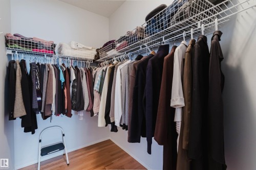 Walk-in closet featuring wire shelving, multiple hanging rods, and wood-finish flooring - 19 1659 Jamha Road, Edmonton, AB - Indoor With Storage