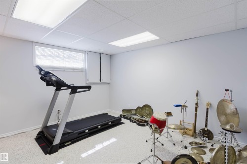 Finished room featuring textured flooring, painted walls, and drop ceiling with integrated lighting - 19 1659 Jamha Road, Edmonton, AB - Indoor Photo Showing Gym Room