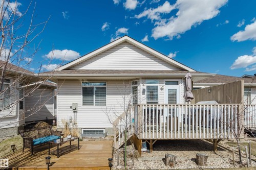 Exterior rear elevation featuring light-colored siding, a multi-level wooden deck, and a gravel ground cover - 19 1659 Jamha Road, Edmonton, AB - Outdoor With Deck Patio Veranda