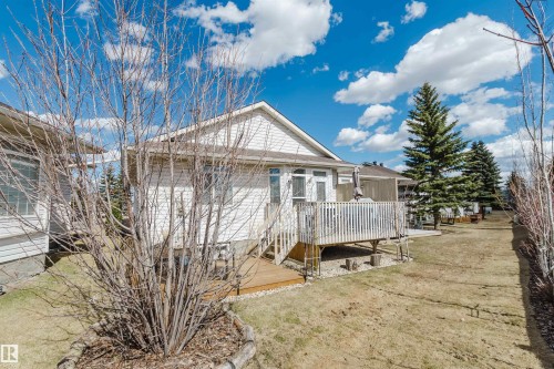 White siding exterior with a multi-level wood deck, featuring white railings and steps - 19 1659 Jamha Road, Edmonton, AB - Outdoor