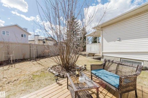 Rear exterior featuring a wood-plank deck, white vinyl siding, a privacy fence, and a large deciduous tree - 19 1659 Jamha Road, Edmonton, AB - Outdoor With Deck Patio Veranda With Exterior