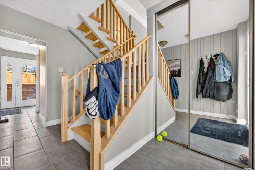 Staircase with natural wood handrails and treads, complemented by gray wall paneling - 1 Greenwich Crescent, St. Albert, AB - Indoor Photo Showing Other Room