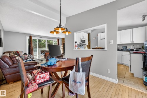 Open concept dining area featuring wood-finish flooring and a three-light pendant fixture - 1 Greenwich Crescent, St. Albert, AB - Indoor