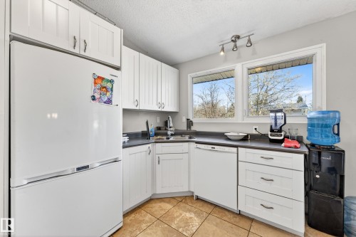 Kitchen featuring white shaker-style cabinetry, dark countertops, and tile flooring - 1 Greenwich Crescent, St. Albert, AB - Indoor Photo Showing Kitchen