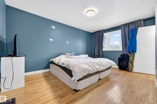 Bedroom featuring wood-finish flooring, a bright window, and a built-in closet with white doors - 1 Greenwich Crescent, St. Albert, AB - Indoor Photo Showing Bedroom