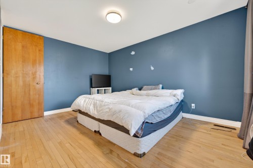Spacious room featuring wood-finish flooring, a light wood-finish door, and a flush-mount ceiling light - 1 Greenwich Crescent, St. Albert, AB - Indoor Photo Showing Bedroom