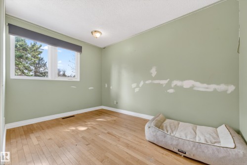 Room featuring wood-finish flooring, a double window with a dark roller blind, and light green walls - 1 Greenwich Crescent, St. Albert, AB - Indoor Photo Showing Other Room