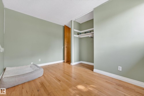 Room featuring wood-finish flooring, light green walls, white trim, and a white popcorn ceiling - 1 Greenwich Crescent, St. Albert, AB - Indoor Photo Showing Other Room