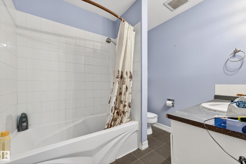 Bathroom featuring a white bathtub, white subway tile surround, dark grey floor tiles, and a vanity with an integrated sink - 1 Greenwich Crescent, St. Albert, AB - Indoor Photo Showing Bathroom