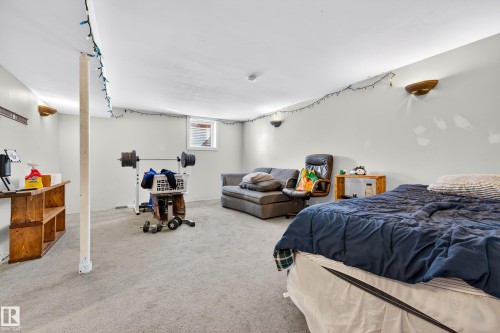 Expansive carpeted room featuring a white ceiling and walls, a window providing natural light, and wall-mounted sconce lighting - 1 Greenwich Crescent, St. Albert, AB - Indoor Photo Showing Bedroom
