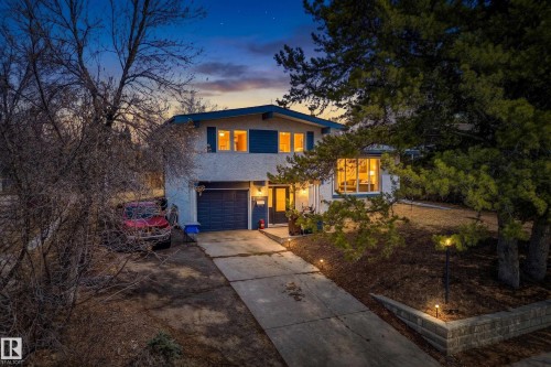 Split-level residence featuring a two-car garage with a dark blue door, concrete driveway, and exterior wall sconces - 1 Greenwich Crescent, St. Albert, AB - Outdoor