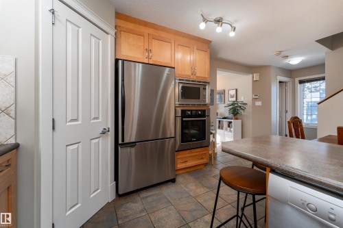 Kitchen with stainless steel appliances, dark countertops, light wood finish cabinets, and a breakfast bar area - 10906 72 Avenue, Edmonton, AB - Indoor Photo Showing Kitchen With Stainless Steel Kitchen