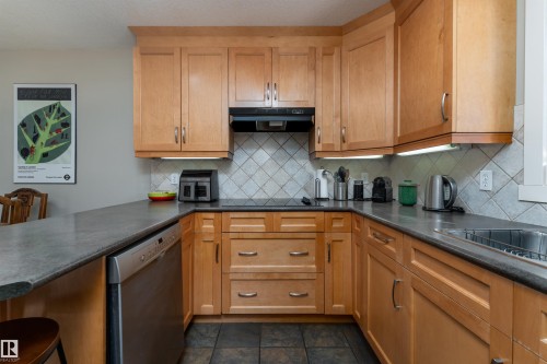 Kitchen featuring dark countertops, dishwasher, a kitchen bar, a peninsula, and backsplash - 10906 72 Avenue, Edmonton, AB - Indoor Photo Showing Kitchen