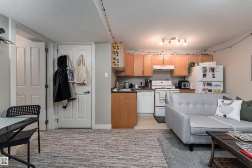 Kitchen with white appliances, dark countertops, a textured ceiling, and light wood finish cabinetry - 10906 72 Avenue, Edmonton, AB - Indoor Photo Showing Kitchen