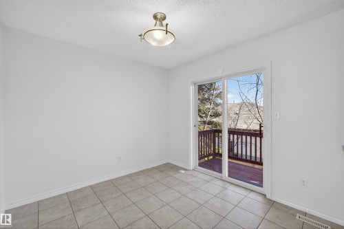 Room featuring neutral tile flooring, white baseboards, and a glass sliding door providing access to an exterior wood deck - 6 1237 Carter Crest Road, Edmonton, AB 