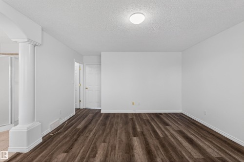 Spacious interior featuring wood-finish flooring, white painted walls, and a contemporary flush-mount ceiling light - 6 1237 Carter Crest Road, Edmonton, AB 