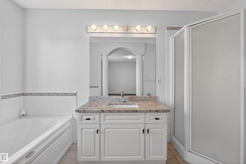 Bathroom featuring a single vanity with stone-finish countertop, undermount sink, and white cabinetry - 6 1237 Carter Crest Road, Edmonton, AB 