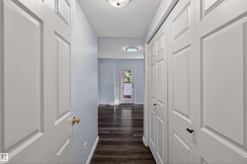 Hallway featuring wood-finish flooring, light blue wall paint, and white paneled doors - 6 1237 Carter Crest Road, Edmonton, AB 
