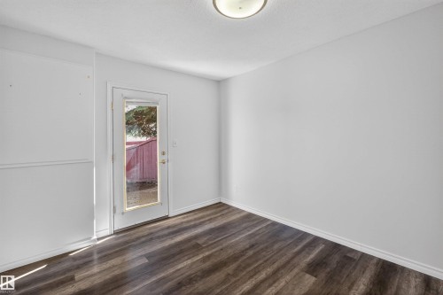 Expansive room featuring wood-finish flooring, white baseboards, and a glass-paneled exterior door - 6 1237 Carter Crest Road, Edmonton, AB 