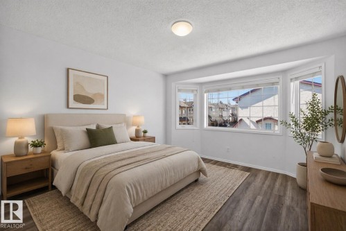 Bright bedroom featuring a bay window, wood-finish flooring, white walls, and a flush-mount ceiling light - 6 1237 Carter Crest Road, Edmonton, AB 