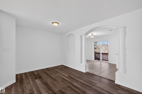 Expansive room featuring wood-finish flooring, white baseboards, and a semi-flush mount ceiling light - 6 1237 Carter Crest Road, Edmonton, AB 