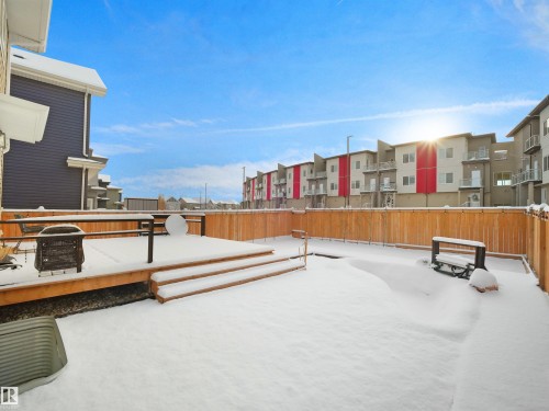 Expansive backyard featuring a wood deck with steps, a full-height wooden privacy fence, and a snow-covered lawn - 20827 130 Avenue Nw, Edmonton, AB - Outdoor