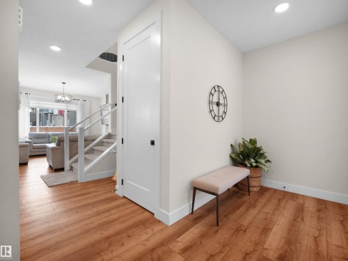 Entryway featuring warm wood-finish flooring, recessed lighting, white baseboards, and a contemporary staircase with white railings - 20827 130 Avenue Nw, Edmonton, AB - Indoor Photo Showing Other Room