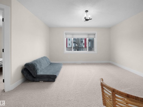 Spacious room featuring neutral carpeting, a large window with blinds, and a contemporary ceiling light fixture - 20827 130 Avenue Nw, Edmonton, AB - Indoor