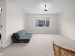 Spacious room featuring neutral carpeting, a large window with blinds, and a contemporary ceiling light fixture - 