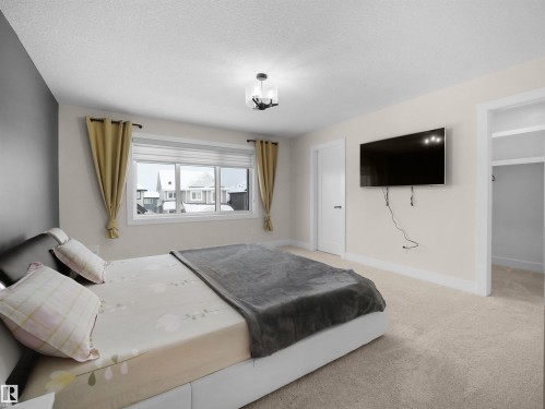 Spacious room featuring neutral carpeting, a large window, a ceiling-mounted light fixture, and a doorway opening to an additional area - 20827 130 Avenue Nw, Edmonton, AB - Indoor Photo Showing Bedroom