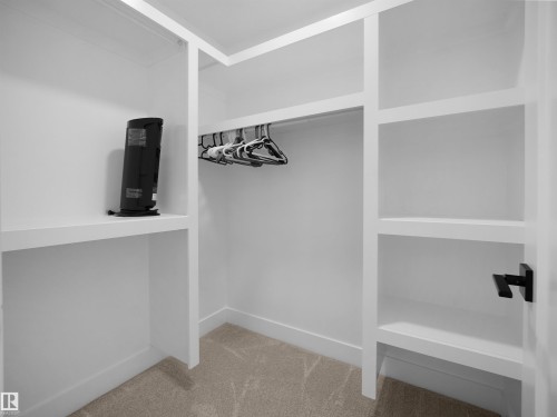 Custom closet system featuring white built-in shelving, integrated hanging rods, and neutral carpet flooring - 20827 130 Avenue Nw, Edmonton, AB - Indoor Photo Showing Other Room