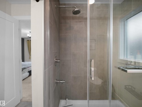 Glass-enclosed shower with full-height tile surround, rain shower head, and an integrated bathtub filler - 20827 130 Avenue Nw, Edmonton, AB - Indoor Photo Showing Bathroom