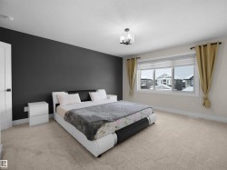Spacious room featuring a large window, neutral carpeting, a dark accent wall, a solid white door, and a contemporary ceiling fixture - 