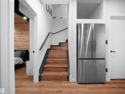 Staircase featuring wood-finish treads and risers with a contrasting black handrail - 