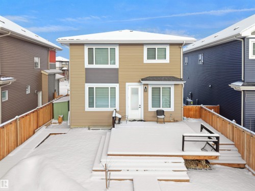 Rear exterior featuring a spacious wooden deck with integrated bench seating, privacy fencing, and a light-toned siding facade - 20827 130 Avenue Nw, Edmonton, AB - Outdoor With Exterior